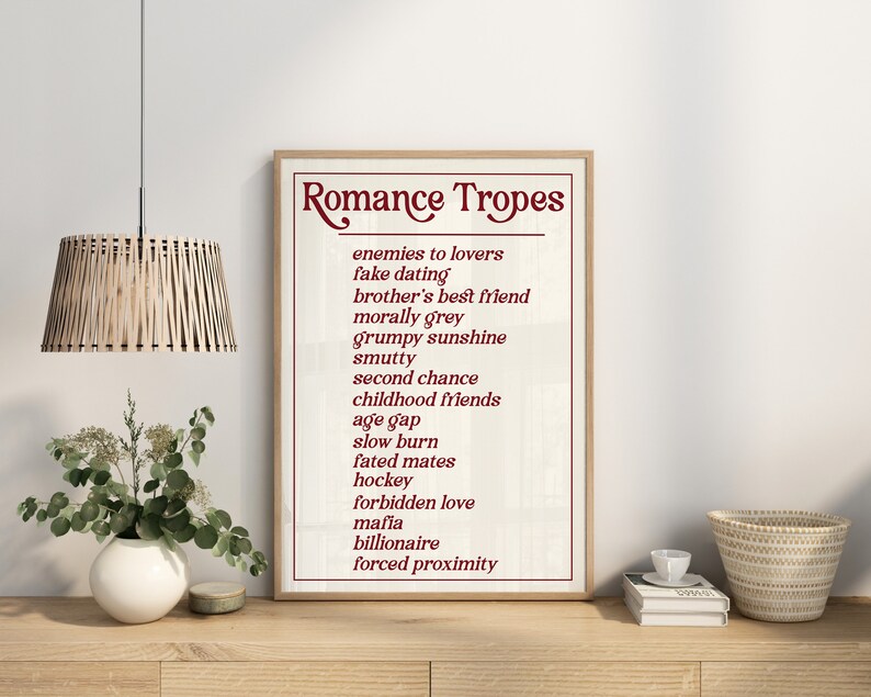 Puede incluir: Una impresi&oacute;n enmarcada con el t&iacute;tulo "Romance Tropes" y una lista de tropos rom&aacute;nticos comunes en texto rojo sobre un fondo blanco.