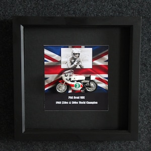 Puede incluir: Impresión enmarcada en negro que representa una motocicleta vintage y un corredor frente a una bandera de la Union Jack. La impresión incluye el texto "Phil Read MBE" y "1968 250cc & 500cc World Champion".
