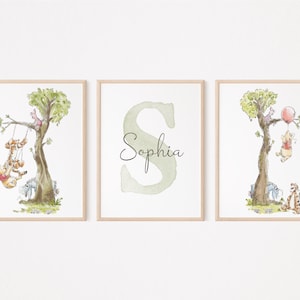 May include: Three Winnie the Pooh themed prints for a nursery or child's room. The first print features Winnie the Pooh and Tigger on a swing. The second print features the letter S with the name Sophia written in cursive. The third print features Winnie the Pooh holding a balloon with Piglet, Eeyore, and Tigger below.