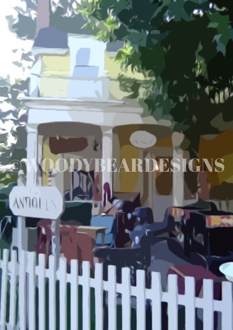 May include: A yellow building with a white picket fence in front of it. The building has a sign that says "Antiques" and a sign that says "Woodybeard Designs". There are several chairs and tables in front of the building.