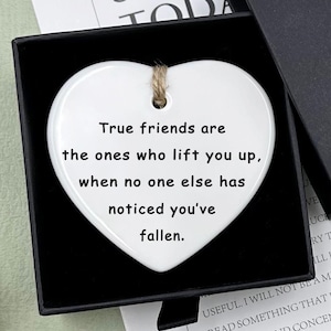 May include: White ceramic heart-shaped ornament with the text "True friends are the ones who lift you up, when no one else has noticed you've fallen." The ornament is in a black gift box with a "Hand made" tag.