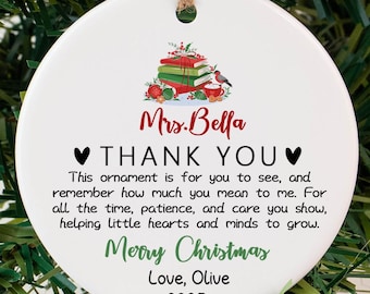 May include: A white ceramic Christmas ornament with a printed message. The ornament has a string for hanging and features text that reads "Mrs. Bella THANK YOU Merry Christmas Love, Olive 2025".