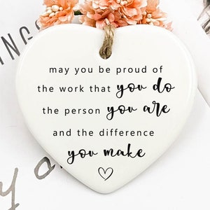 Könnte beinhalten: Weißer, herzförmiger Anhänger aus Keramik mit dem Text "may you be proud of the work that you do the person you are and the difference you make".