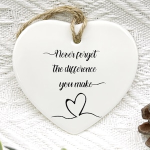 May include: White ceramic heart-shaped ornament with the text "Never forget the difference you make" and a small heart design.