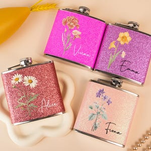 Può includere: Quattro fiaschette in acciaio inossidabile personalizzate con finiture glitter e motivi floreali. Le fiaschette sono rosa, viola, rosso e pesca. I nomi Vivian, Emma, Alice e Fiona sono stampati sulle fiaschette.