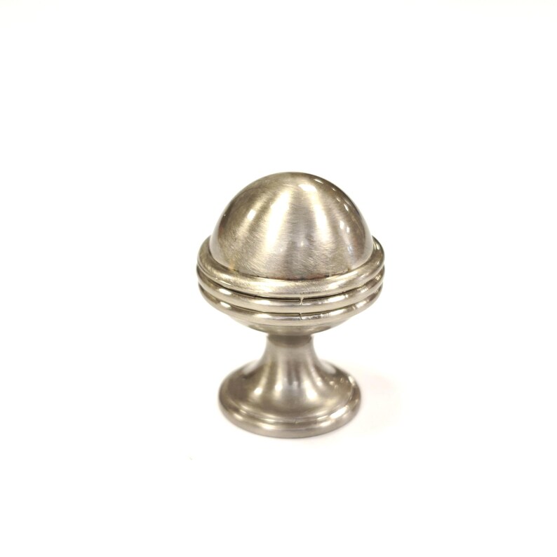 May include: A brushed nickel cabinet knob with a spherical top and a pedestal base. The knob features a layered design below the sphere and is set against a white background. This hardware is suitable for drawers and cabinets.