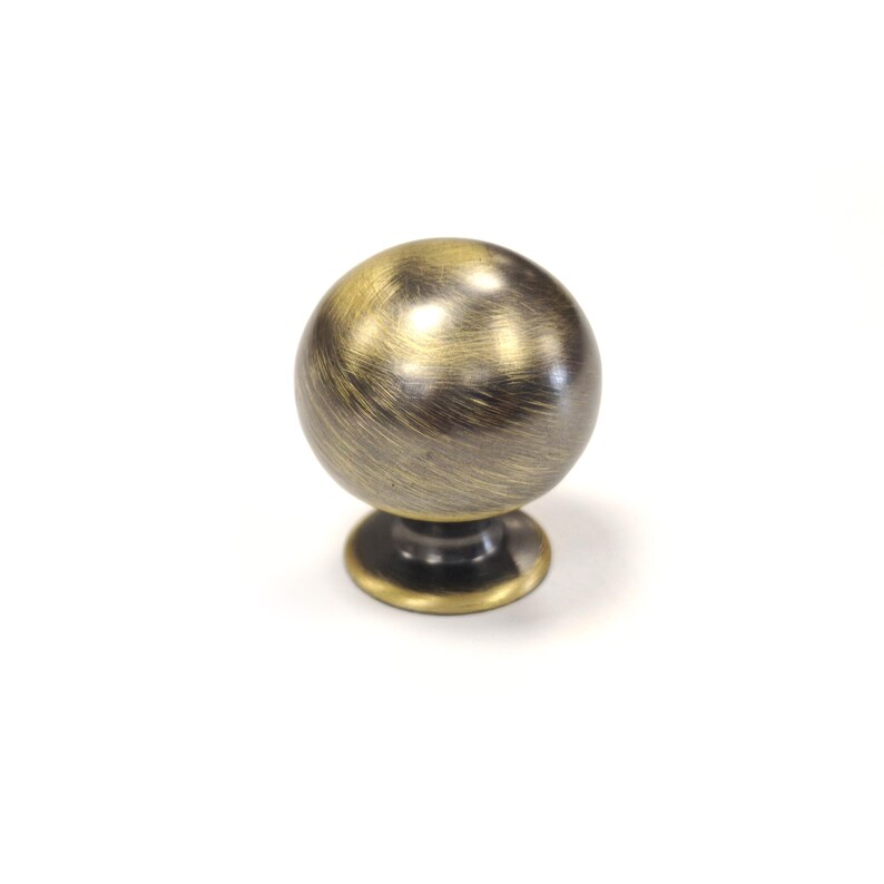 Op de afbeelding: Bronzen kastknop met een bolvormig ontwerp. De knop heeft een geborstelde afwerking en staat op een kleine, cirkelvormige basis. Geschikt voor laden, kasten en meubels.