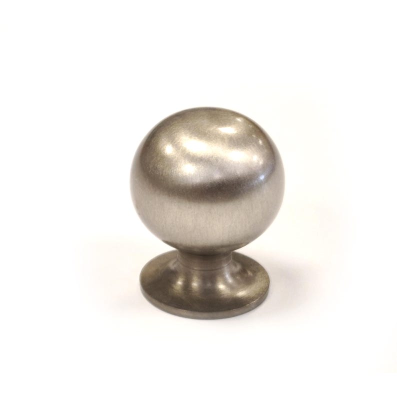 May include: A brushed nickel cabinet knob with a spherical design. The knob has a round base and a smooth, metallic finish. This hardware is suitable for drawers, cabinets, and other furniture.