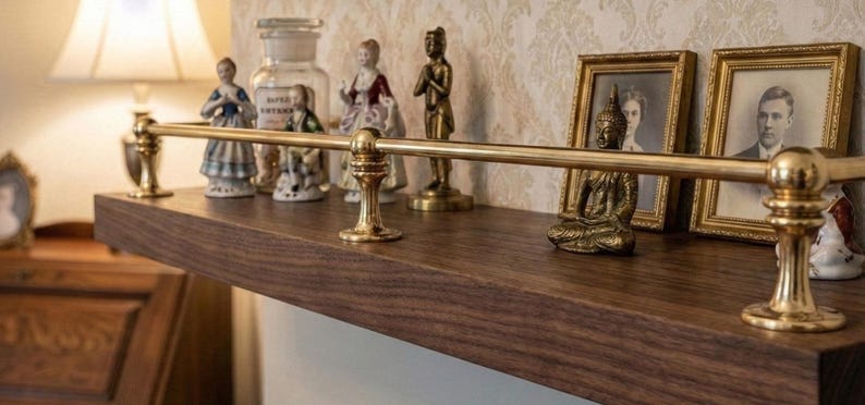 May include: A dark wood shelf with brass accents and decorative items. The shelf holds framed portraits, figurines, and a small Buddha statue. A brass bar runs along the front of the shelf, adding a touch of elegance.