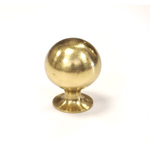 May include: A polished gold-coloured cabinet knob, spherical in shape, with a circular base. This metal furniture hardware is designed for use on cabinets and drawers. The knob is set against a white background.