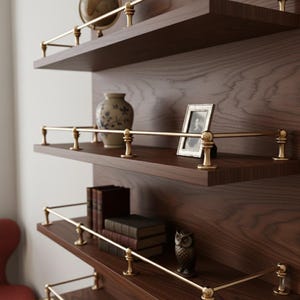 May include: A dark wood wall shelf unit with brass accents. The shelves hold a globe, a vase, a framed photo, books, and an owl figurine. The shelves have a classic, vintage aesthetic.