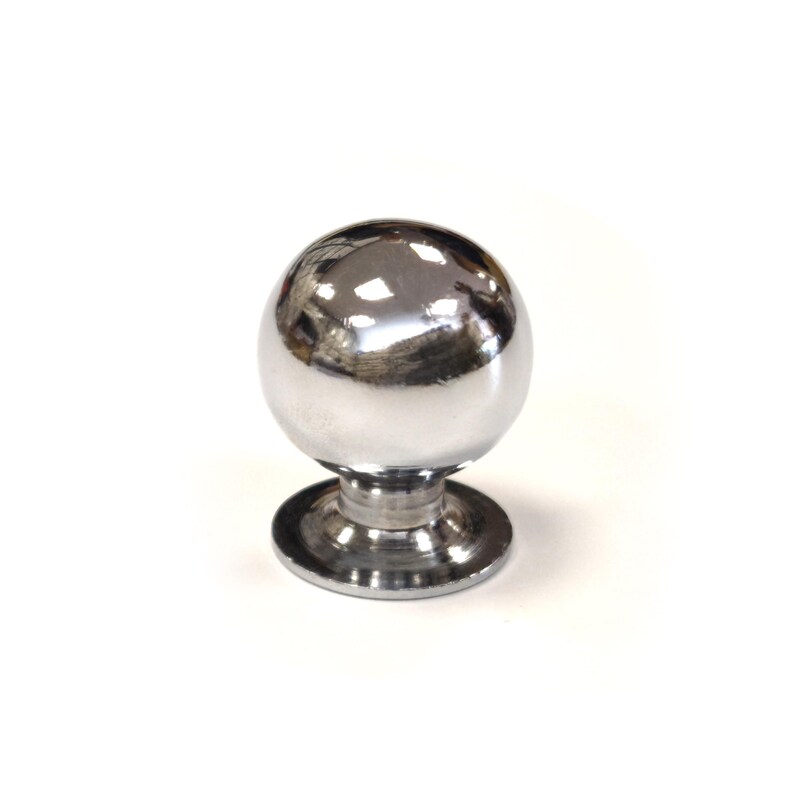 May include: A polished chrome cabinet knob featuring a spherical top and a circular base. The knob reflects light, giving it a bright, metallic look. Suitable for drawers, cabinets, and furniture. The knob's dimensions are in centimetres.