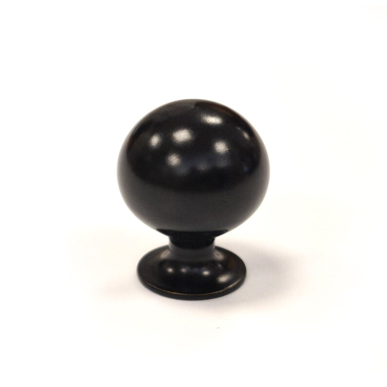 May include: A dark bronze cabinet knob with a spherical design. The knob has a rounded top and a circular base, suitable for furniture hardware. The finish is smooth and reflective, adding a touch of elegance to any cabinet or drawer.