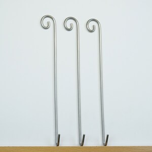 May include: Three silver metal hooks with a loop at the top and a hook at the bottom.