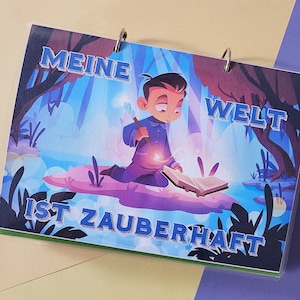 Könnte beinhalten: Eine blaue und violette Illustration eines Jungen mit einem Buch und einem Zauberstab. Der Text lautet "Meine Welt ist Zauberhaft", was "Meine Welt ist magisch" bedeutet.
