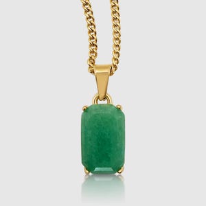 Puede incluir: Un collar dorado con un colgante rectangular verde esmeralda. El colgante cuelga de una cadena dorada. El colgante tiene forma rectangular con esquinas redondeadas. La cadena es de estilo cadena de bordillo.