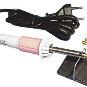 Könnte beinhalten: Ein weißes und rosa elektrisches Lötkolben mit einem schwarzen Kabel und einem schwarzen Ständer. Der Lötkolben hat eine schwarze Spitze und wird mit einem Satz goldfarbener Metallspitzen geliefert.