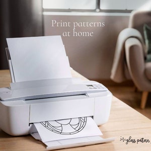 K&ouml;nnte beinhalten: Ein wei&szlig;er Drucker mit einem Blatt Papier, das durch ihn gef&uuml;hrt wird. Das Papier hat ein schwarz-wei&szlig;es Glasmalereimuster darauf gedruckt. Der Text "Drucken Sie Muster zu Hause" ist &uuml;ber dem Drucker sichtbar. Der Text "Glasmusterzone" ist unter dem Drucker sichtbar.