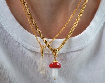 May include: Two gold chains with a red and white mushroom charm and a clear glass charm hanging from them.