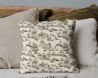 May include: A white throw pillow with a brown and white toile pattern featuring a repeating design of houses, trees, and people. The pillow is sitting on a bed with other pillows.