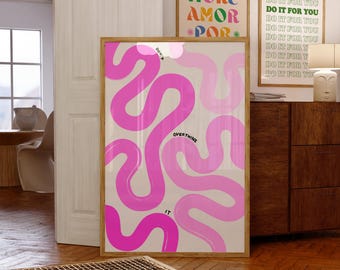 May include: A rectangular framed wall art print featuring a light beige background with abstract, winding, wavy lines in shades of hot pink and light pink. The text "DON'T OVERTHINK IT" is printed in small black letters along the wavy lines.