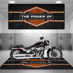 Puede incluir: Motocicleta negra con detalles cromados sobre una alfombra negra y naranja con el texto "Forever The Power Of Freedom".