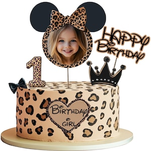 Könnte beinhalten: Ein runder Geburtstagskuchen mit Leopardenmuster. Der Kuchen ist mit einem Foto eines Kindes, der Zahl eins, einer schwarzen Schleife, einer Krone und einem "Happy Birthday"-Kuchenaufsatz verziert. Der Kuchen hat auch ein Herz mit der Aufschrift "Birthday Girl".