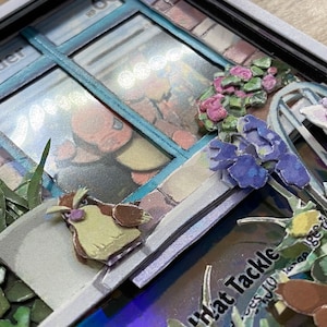 May include: A close-up of a papercraft Pokemon card with a 3D pop-up effect. The card features a blue window with a Pokemon character inside. The window is surrounded by flowers and a small bird. The card text reads 'What Tackle' and '...less you learn to be yourself.'