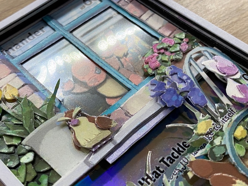 May include: A close-up of a papercraft Pokemon card with a 3D pop-up effect. The card features a blue window with a Pokemon character inside. The window is surrounded by flowers and a small bird. The card text reads 'What Tackle' and '...less you learn to be yourself.'