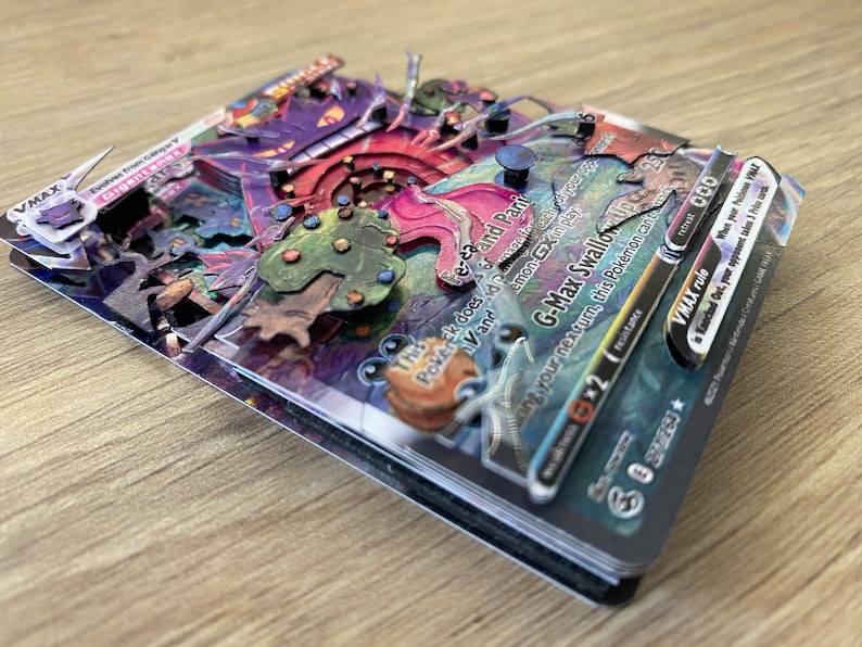 May include: A G-Max Swallow VMAX Pokemon card with a purple, pink, and green illustration. The card has a black border and features the text 'G-Max Swallow Up 2' and 'This Pokemon does -3 damage to itself and Paralyzes itself.' The card also has a VMAX rule that reads: 'When your Pokemon VMAX is Knocked Out, your opponent takes 2 Prize cards.'