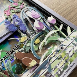 May include: A close-up of a Pokemon card with the text 'Heat Tackle' and 'retreat' visible. The card features a 3D pop-up design with flowers and leaves in shades of green, blue, and purple.