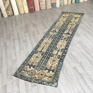 May include: A blue and cream patterned runner rug with a geometric design. The rug is on a light gray wood floor.