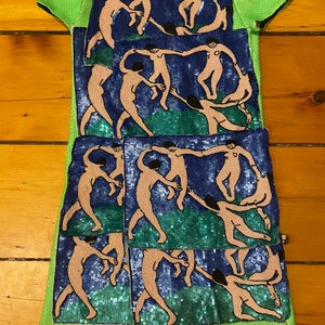 May include: A green sequined dress with multiple embroidered patches of a painting of people dancing in a circle. The patches are in shades of blue, green, and pink.