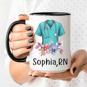 May include: White ceramic mug with a black rim. The mug features a teal blue scrubs top with a stethoscope and a floral design. The text "Sophia, RN" is printed on the mug.