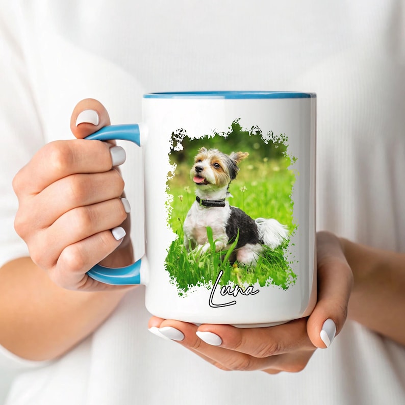 May include: White ceramic mug with a blue handle and rim, featuring a color image of a small dog in green grass. The dog is black, white, and tan. The name "Luna" is written in cursive below the dog.