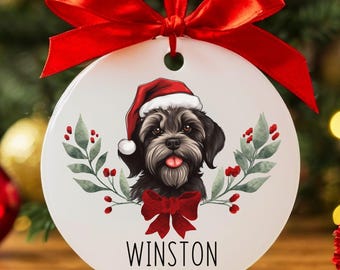 May include: White round Christmas ornament with a black dog wearing a red Santa hat and a red bow. The dog's name is Winston and the year 2025 is printed below.