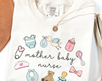 May include: Cream-colored t-shirt with the words "mother baby nurse" surrounded by baby-themed illustrations in pastel colors. A gold necklace with a pendant rests on the shirt.