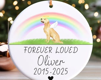May include: White ceramic Christmas ornament with a golden retriever illustration, wings, and a halo under a rainbow. Text reads "FOREVER LOVED Oliver 2015-2025" with a black heart. A gold string is attached for hanging.