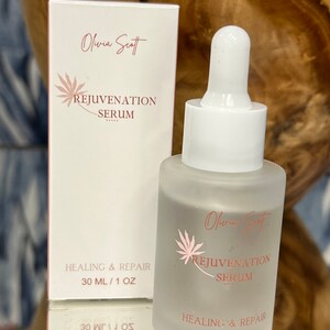May include: A frosted glass bottle and matching box of Olivia Scott Rejuvenation Serum. The bottle has a white dropper and the box and bottle feature the text "Rejuvenation Serum" and "Healing & Repair". The bottle contains 1 fl oz of serum.