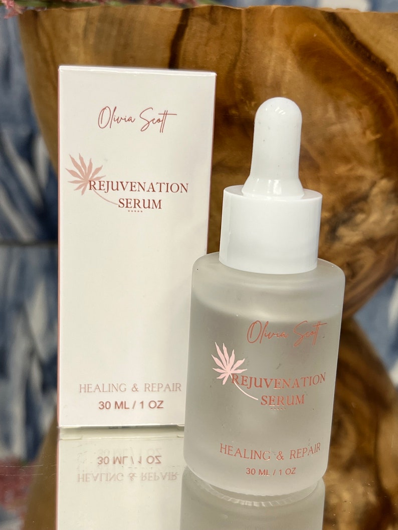 May include: A frosted glass bottle and matching box of Olivia Scott Rejuvenation Serum. The bottle has a white dropper and the box and bottle feature the text "Rejuvenation Serum" and "Healing & Repair". The bottle contains 1 fl oz of serum.
