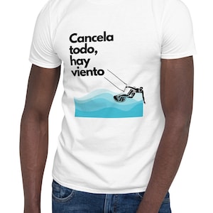 May include: White t-shirt with black text that reads "Cancela todo, hay viento" and a silhouette of a person kitesurfing on blue waves.