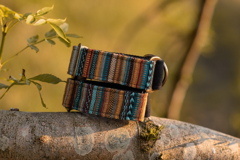 May include: Two colorful dog collars with a geometric pattern in shades of blue, brown, red, and white. The collars are made of fabric and have a metal D-ring.