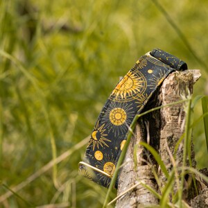 May include: A black and gold dog collar with a celestial pattern featuring suns, moons, and stars.