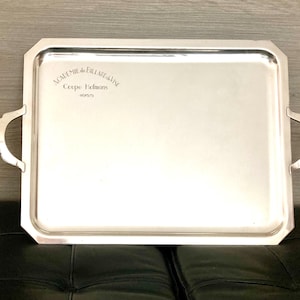 Pode incluir: Uma bandeja de servir de prata com duas alças. A bandeja é gravada com o texto "Academie de l'Art Metallique Coupe Delmas 1935."