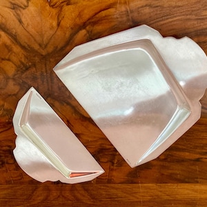 May include: Two silver serving trays with decorative edges. The trays are made of a shiny metal and have a slightly curved shape.