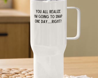 May include: White travel mug with a handle and a clear lid. The mug has the text "YOU ALL REALIZE I'M GOING TO SNAP ONE DAY.....RIGHT?" printed in black. The mug is designed to keep beverages hot or cold.