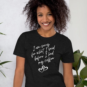 May include: A dark heather grey t-shirt with the text "I am sorry for what I said before I had my coffee" in white lettering. Two white hearts are below the text.