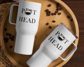 May include: Two white travel mugs with black handles and the text "POT HEAD" and a black graphic of a coffee pot. The mugs are on a wooden tray with coffee beans scattered around them.