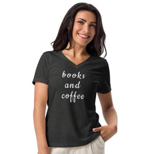 May include: Dark grey v-neck t-shirt with the words "books and coffee" in white script. The shirt is made of a soft material and is being worn by a person.