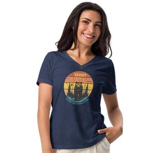 May include: A navy blue v-neck t-shirt with a vintage-style graphic of a bear standing in a forest with a sunset behind it. The graphic says "Resist" and "Support Our National Parks".